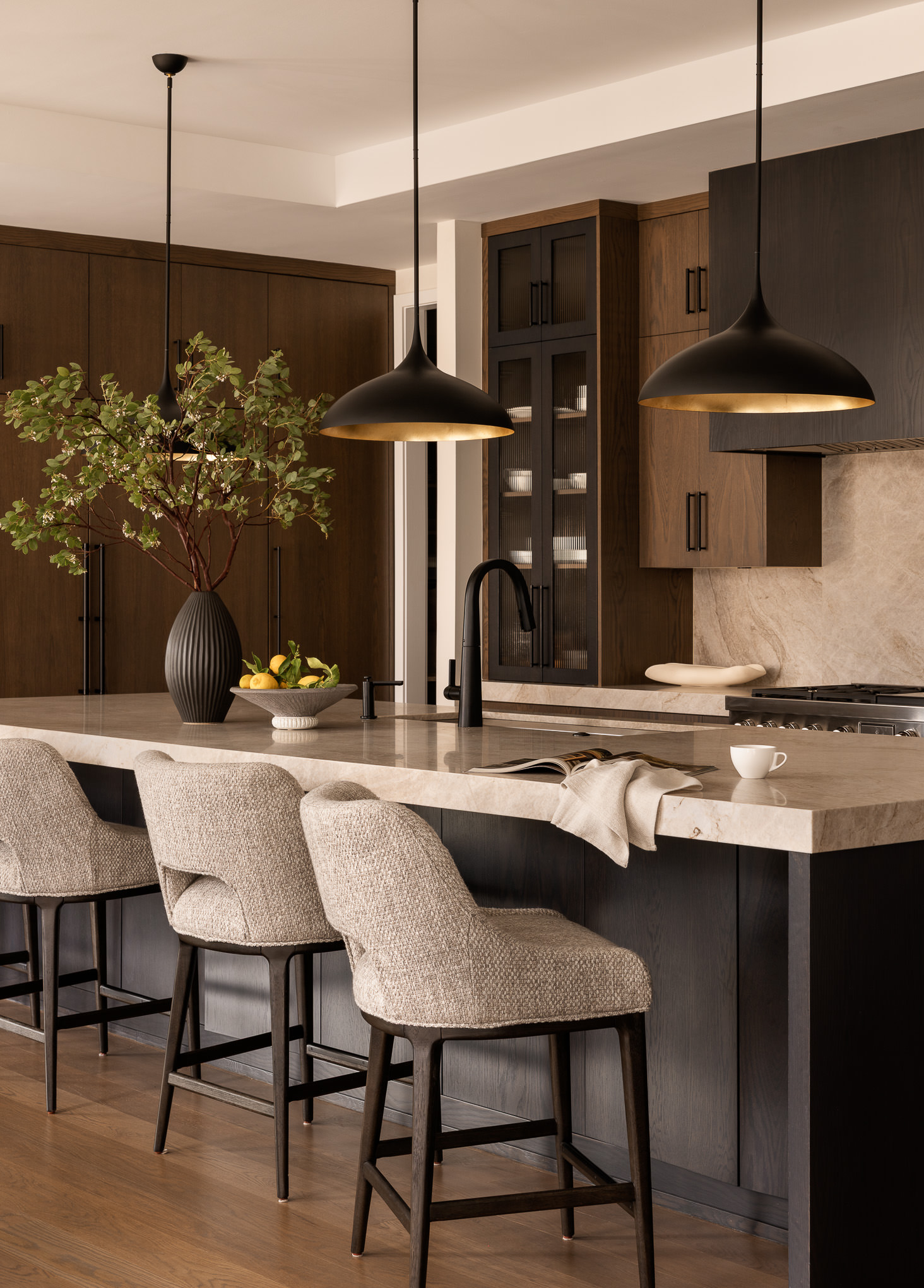 modern kitchen with dark cabinets and warm natural stone countertops