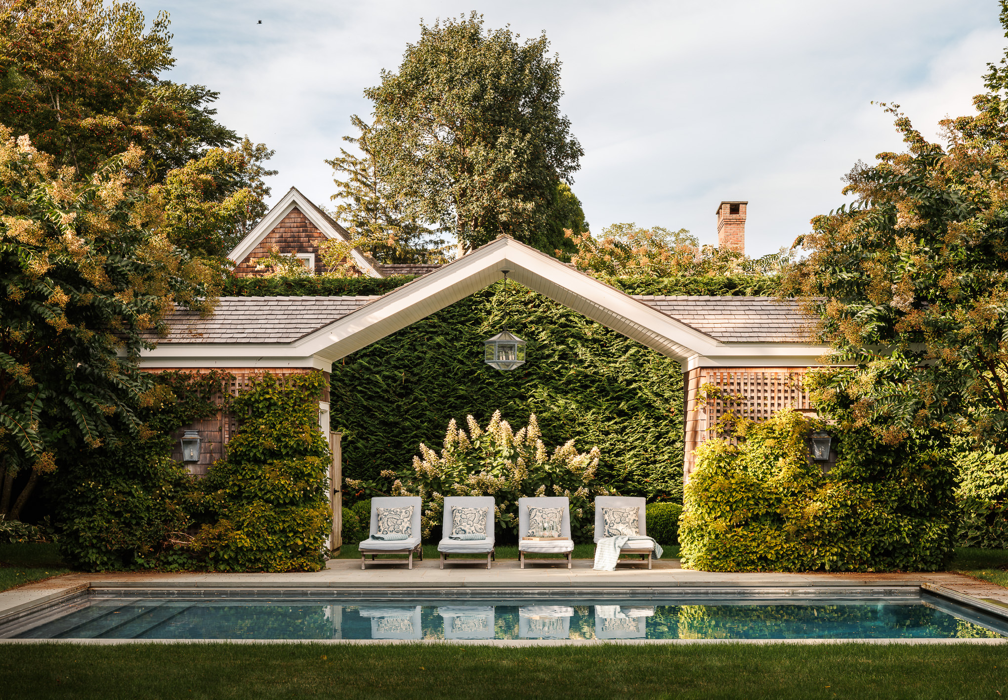 House with an outdoor patio and pool surrounded by trees in East Hampton, NY