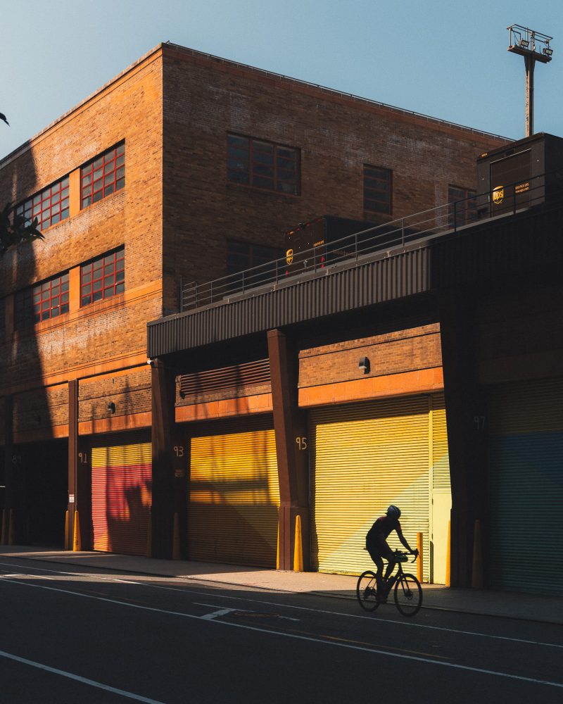 Man cycling in NYC illuminated by light