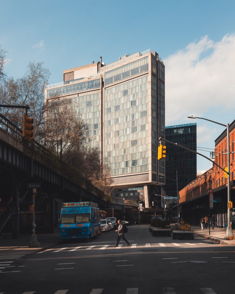 Man illuminated by light walking in front of the Standard Hotel in NYC